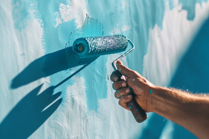 Workers are applying paint containing butyl acrylate on the wall